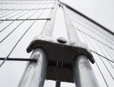 Close-up of galvanised temporary construction fence post coupler and wire mesh panel