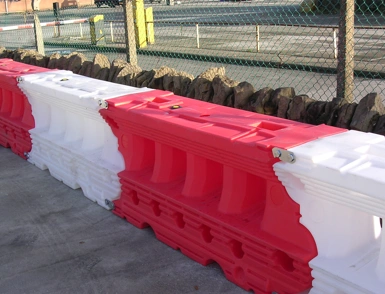 Red and white water-filled plastic road liner barriers lined up along a work zone