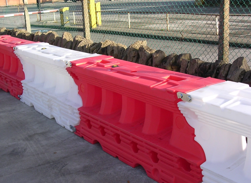 Red and white water-filled plastic road liner barriers lined up along a work zone