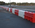 Interlocking red and white water-filled traffic barriers protecting a roadside work area