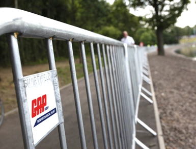 Metal crowd control barriers lining a riverside path for an outdoor event