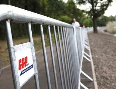 Metal crowd control barriers lining a riverside path for an outdoor event